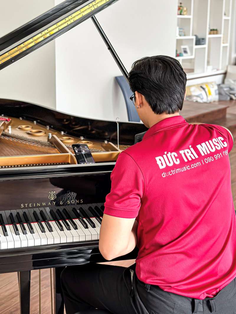 Hình ảnh nhân viên của Piano Đức Trí đang chỉnh sửa dây đàn Piano